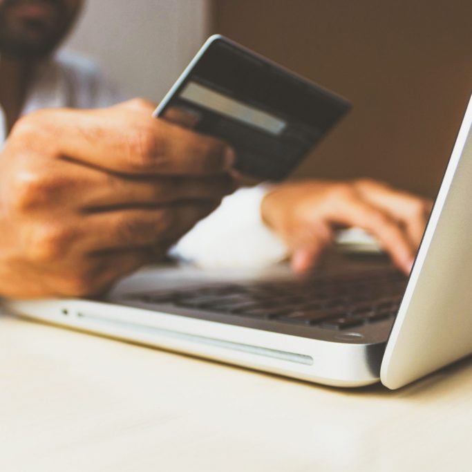 ecommerce - nosweatweb gentleman holding credit card at a laptop computer