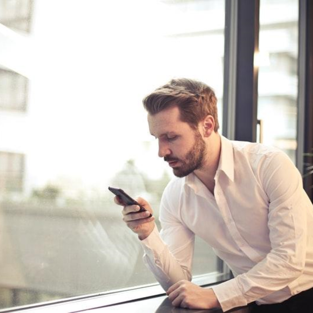 A man looking at a cell phone and searching for local businesses and their websites. Using search engines to find the best web designers in Nashville TN for an affordable business website.